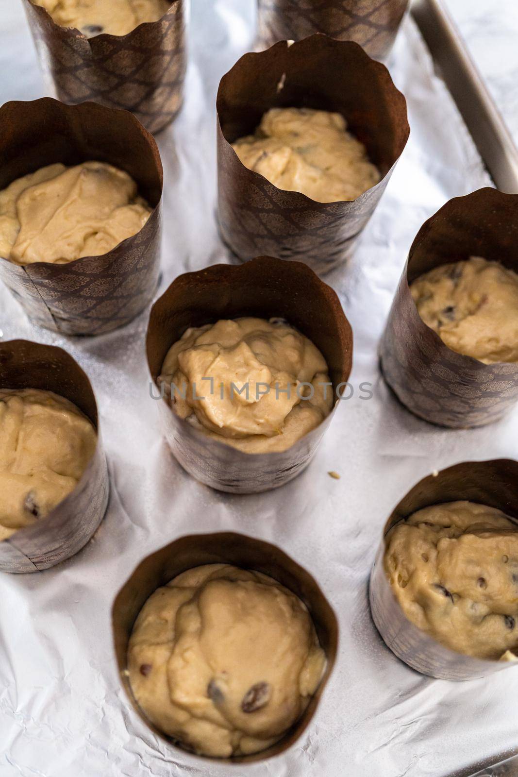 Scooping bread dough into paper liners to bake mini Easter bread kulich.