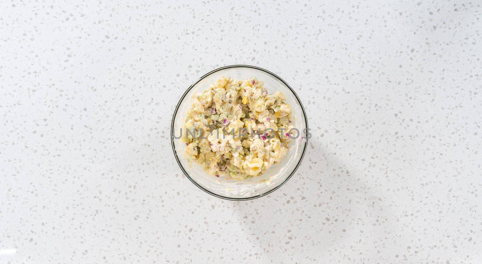 Flat lay. Mixing ingredients in a large glass mixing bowl to make potato salad.