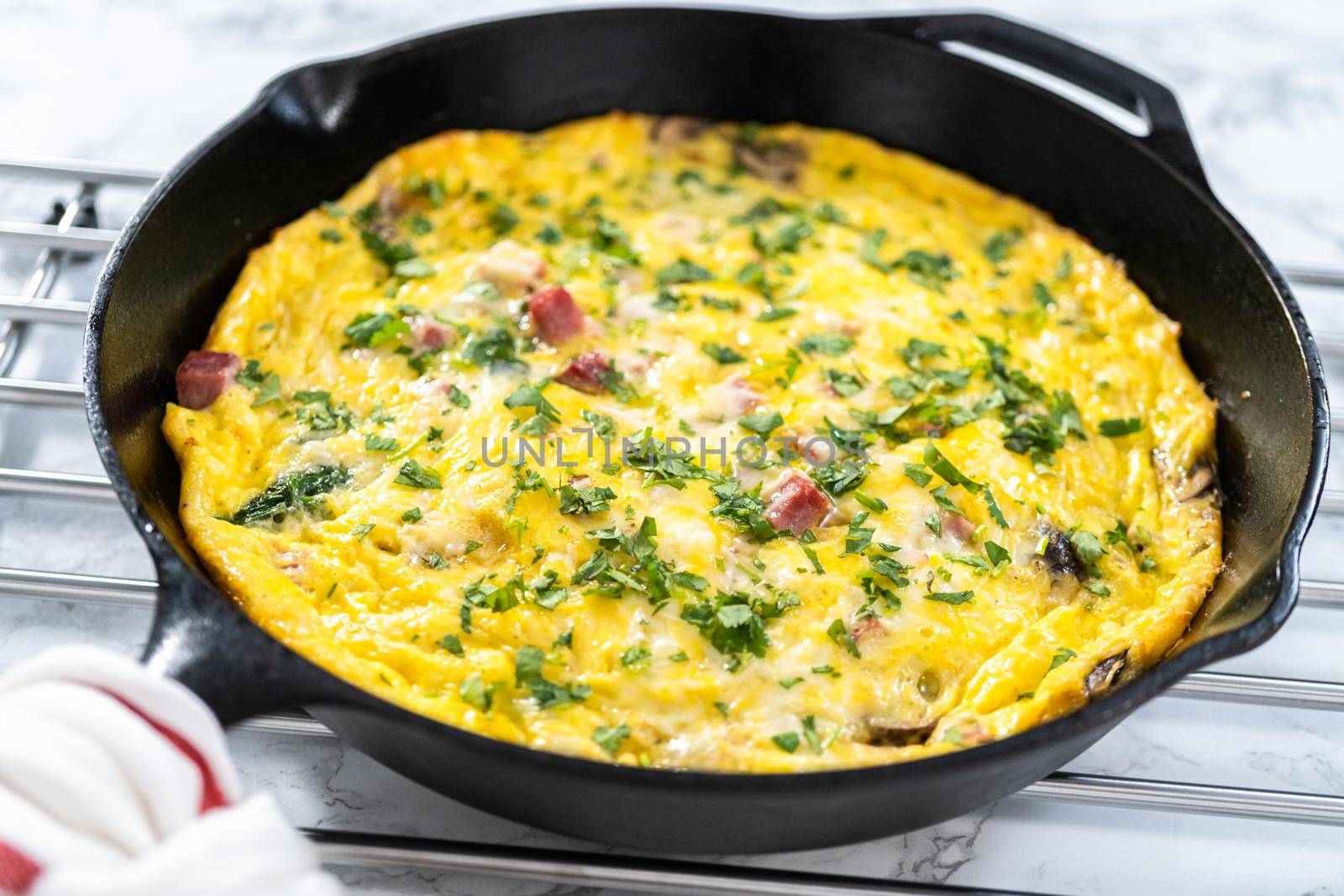 Freshly baked spinach and ham frittata in cast iron skillet.