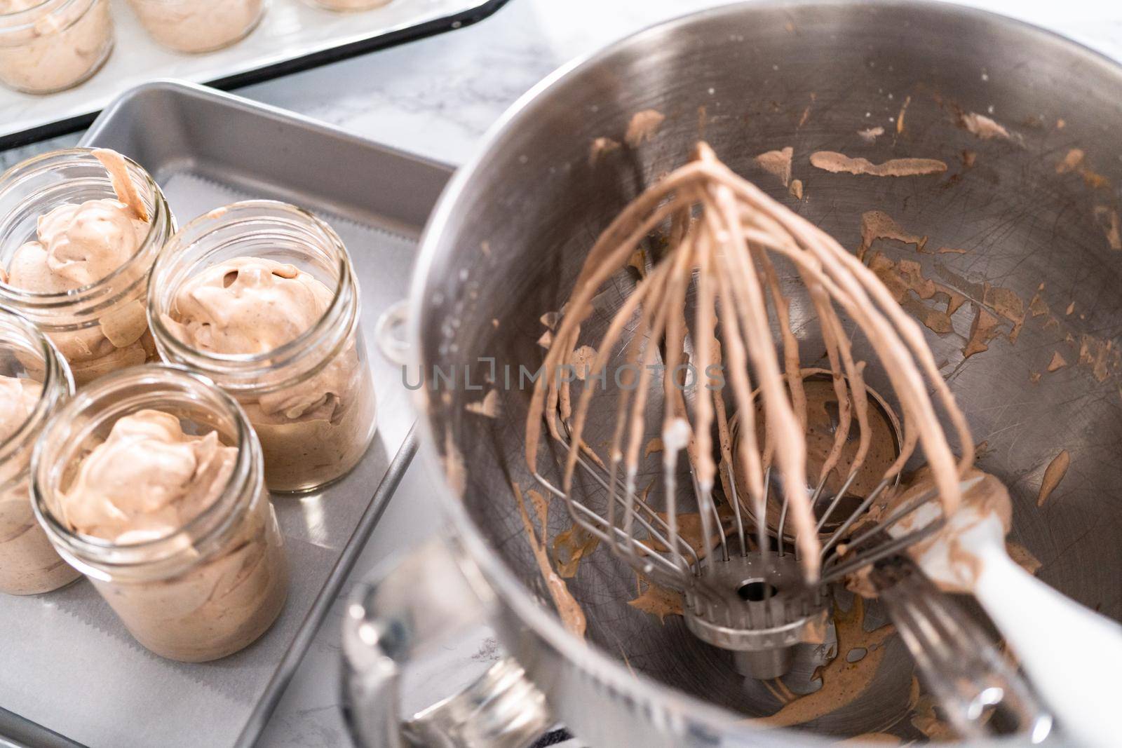 Scooping mixture into the small glass jars to make homemade chocolate ice cream.