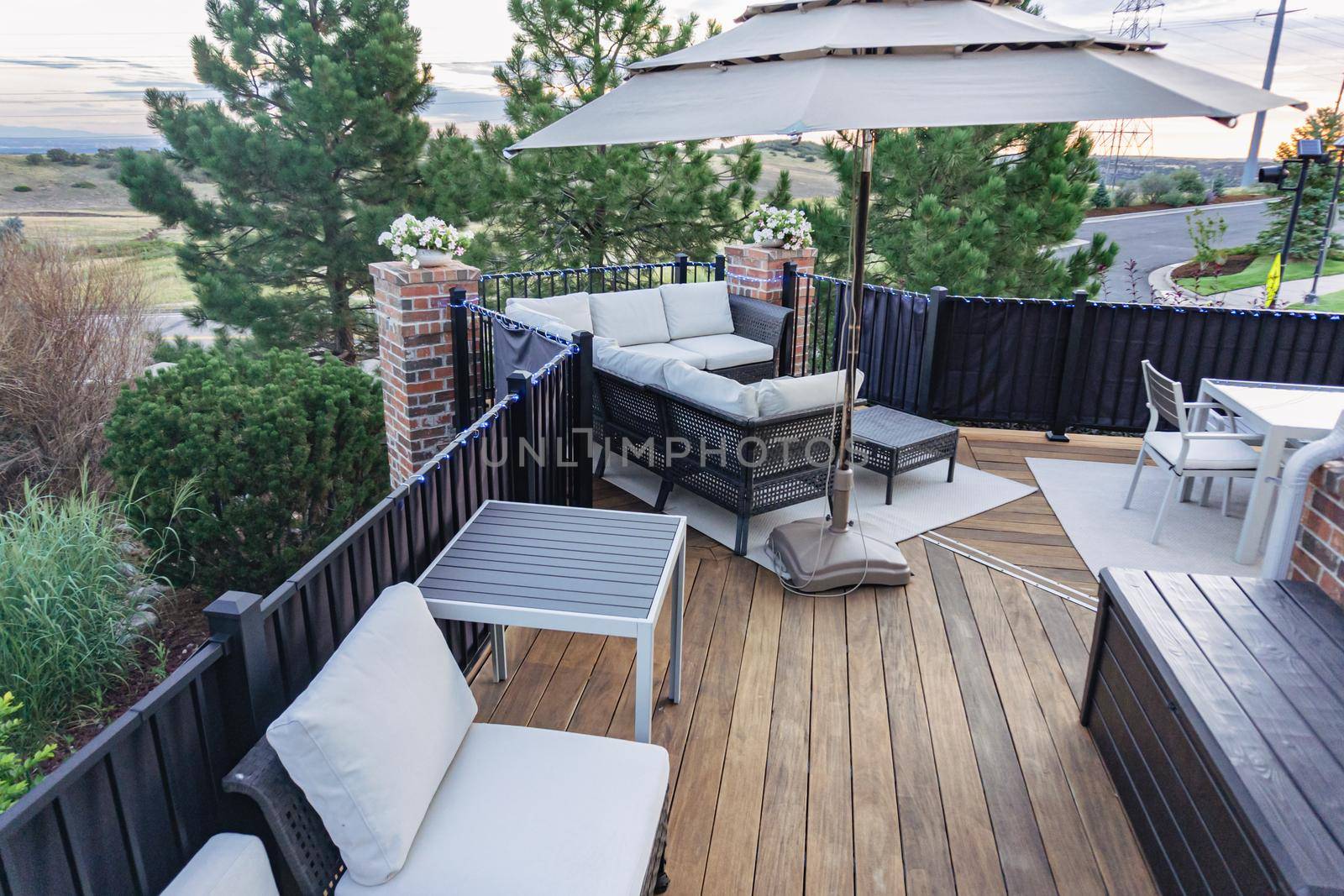 Morning on a summer day. Fully furnished backyard patio with a grill, sitting area, and umbrella.