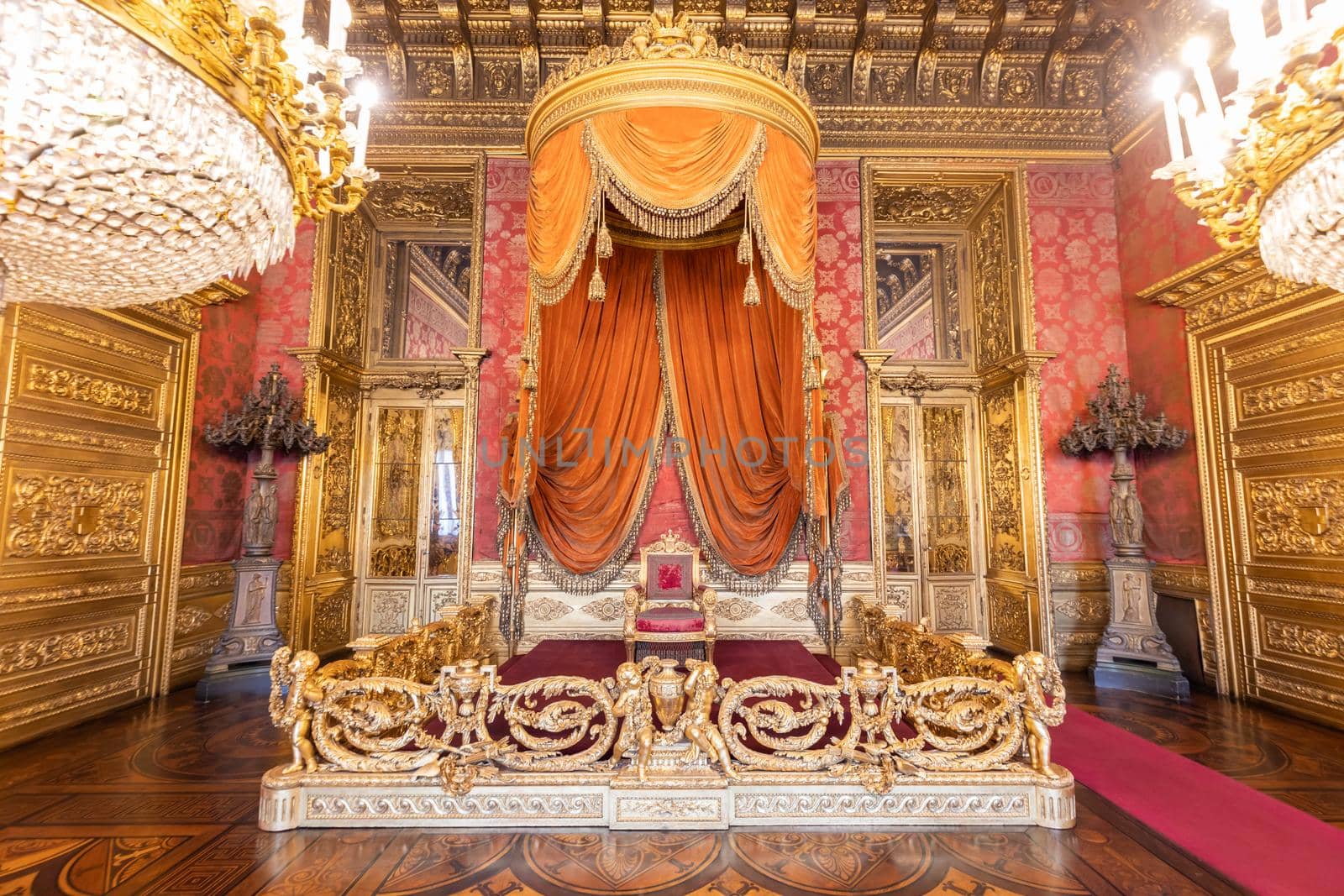 Turin, Italy - Circa August 2021: old throne room interior with chair in luxury palace. Red and gold antique Baroque style - Savoia Royal Palace