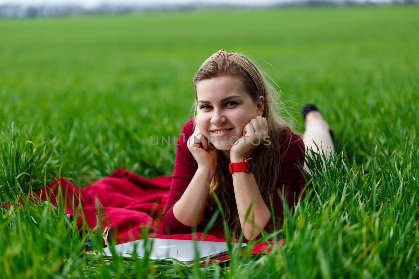 Young beautiful woman student with a laptop lies on the grass. Work outdoors. by Dmitrytph