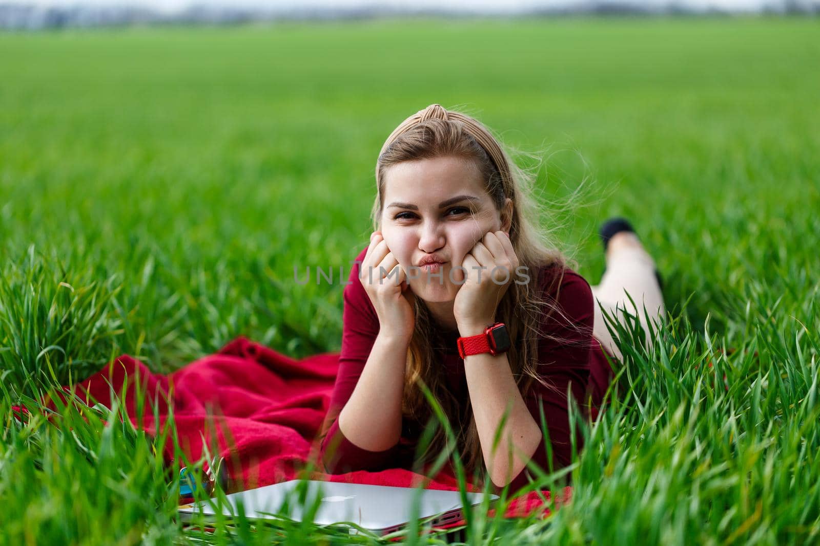 Young beautiful woman student with a laptop lies on the grass. Work outdoors.