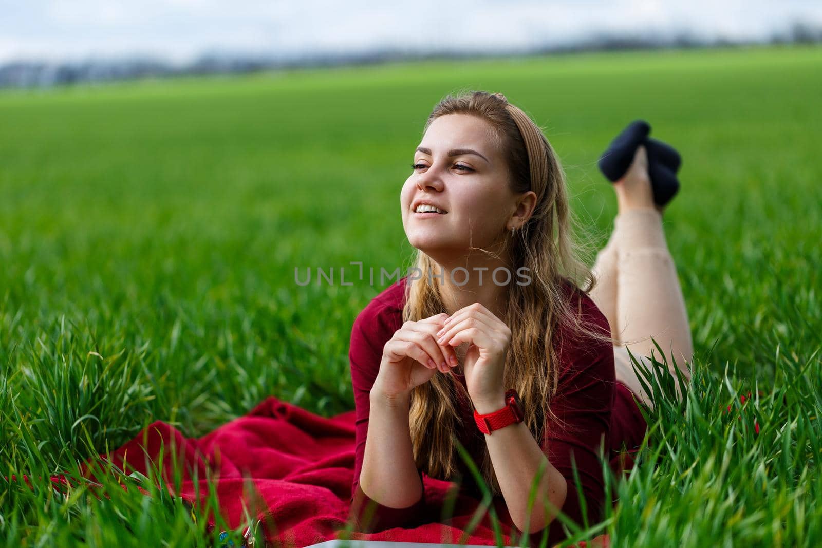 Young beautiful woman student with a laptop lies on the grass. Work outdoors.