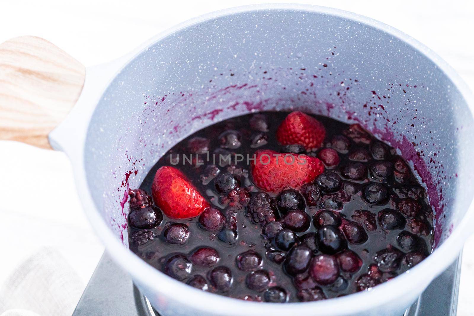 Preparing mixed berry compote from frozen berries in a nonstick cooking pot.