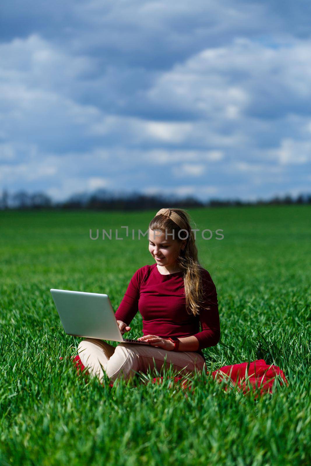 Joyful young girl on the grass with a laptop on her lap. He raised his hands up and laughed. Happiness in the lifestyle of a classical student. Work on the nature. Rest after a good working day.