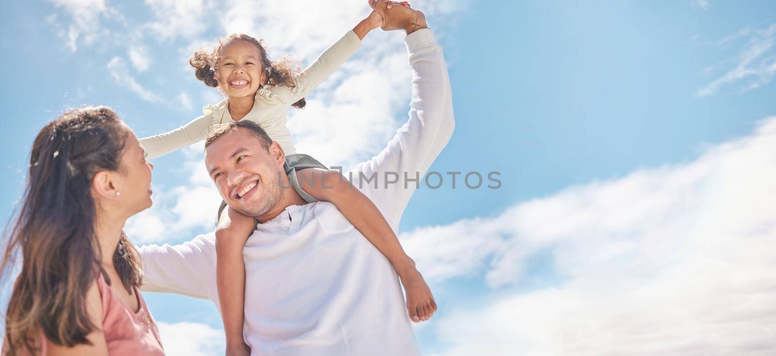 Family, children and love with foster parents and adopted girl outside during day with a blue sky in the background. Mother, father and daughter spending time together and bonding with love and care.