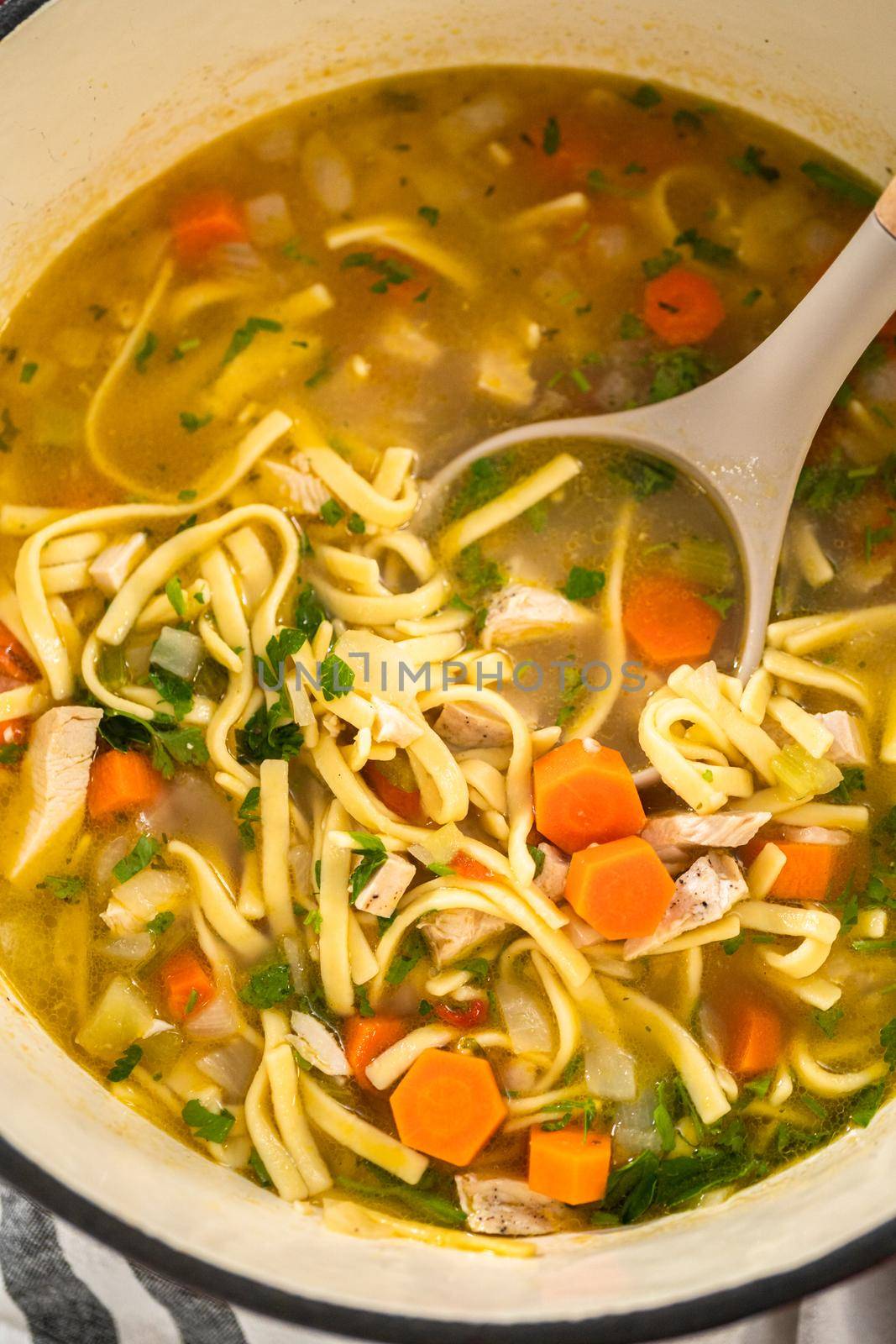 Serving chicken noodle soup with kluski noodles in white ceramic soup bowls.