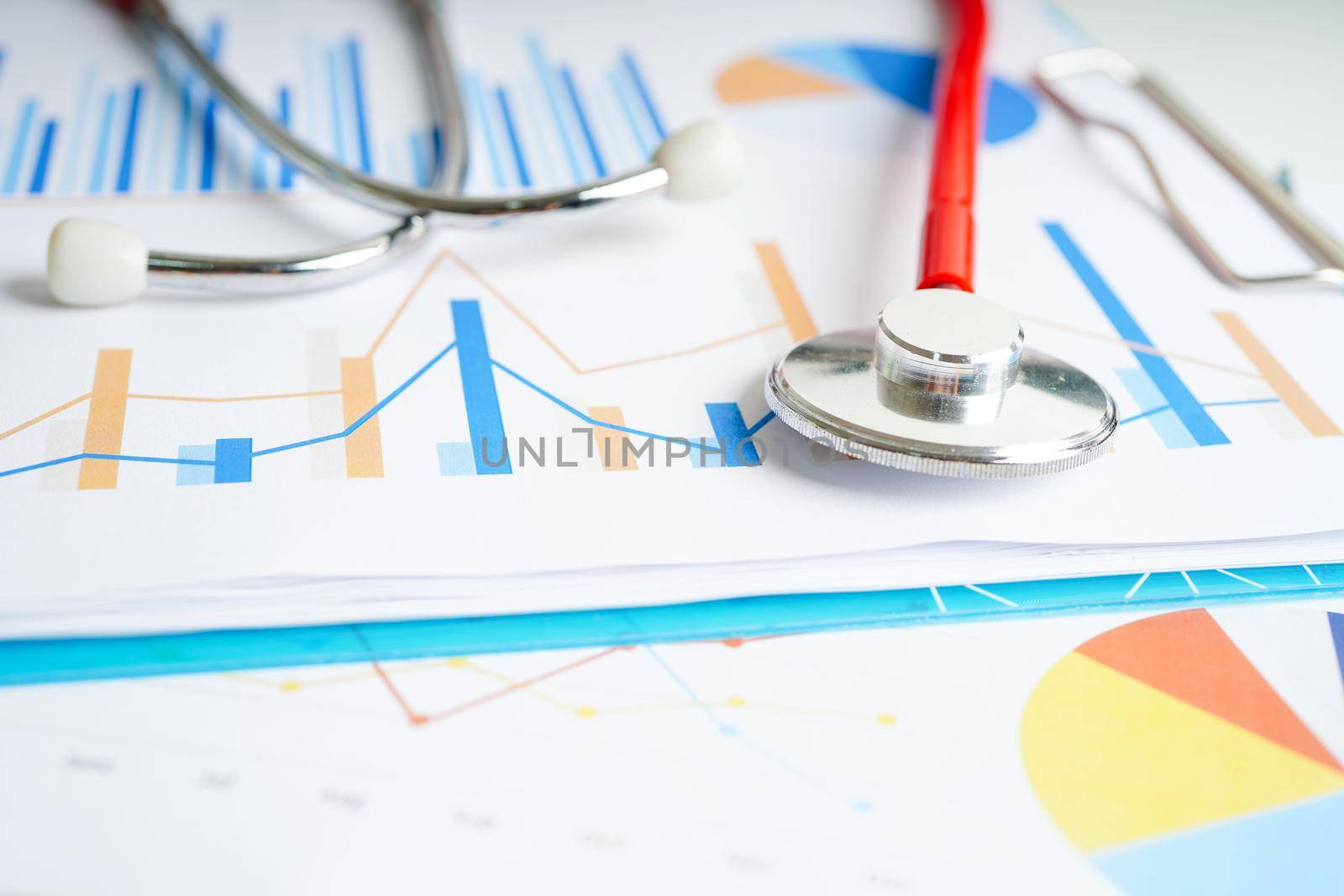 Stethoscope and US dollar banknotes on chart or graph paper, Financial, account, statistics and business data  medical health concept.