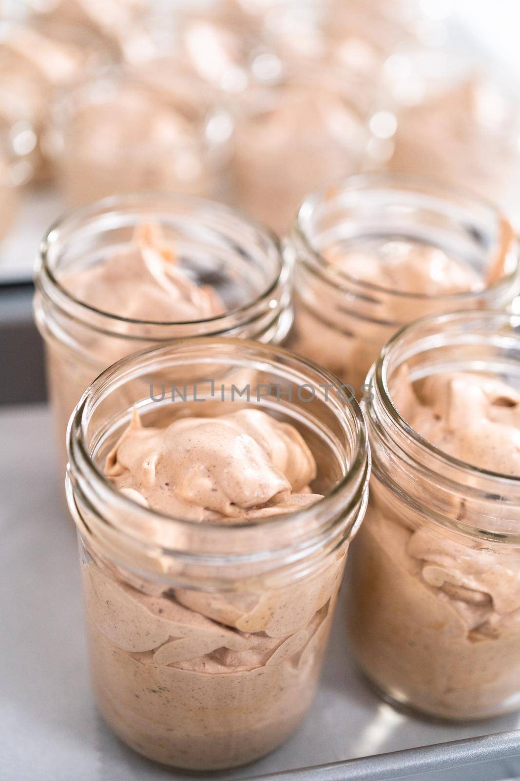 Scooping mixture into the small glass jars to make homemade chocolate ice cream.