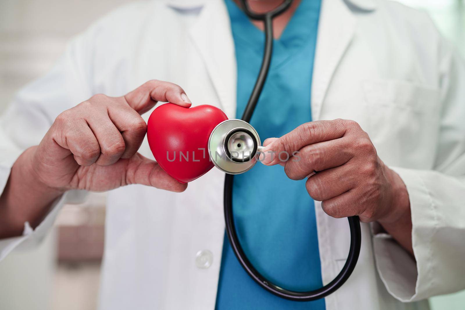 Asian woman doctor holding red heart for health in hospital.