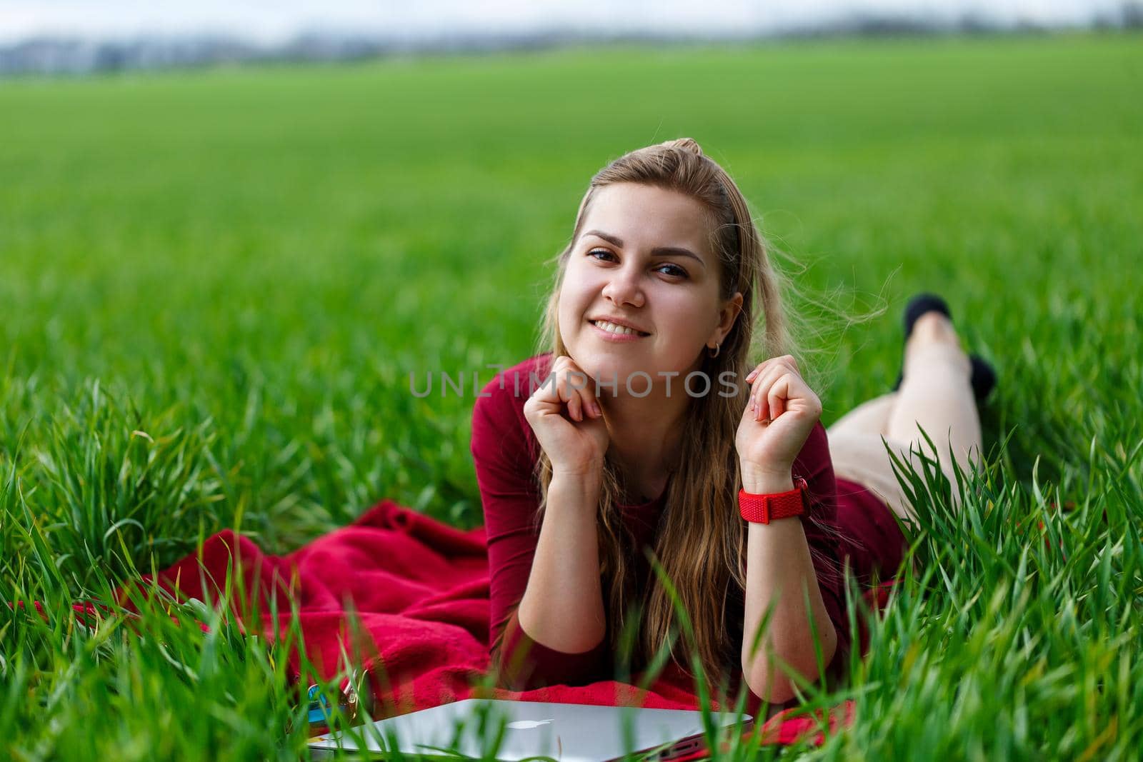 Young beautiful woman student with a laptop lies on the grass. Work outdoors.