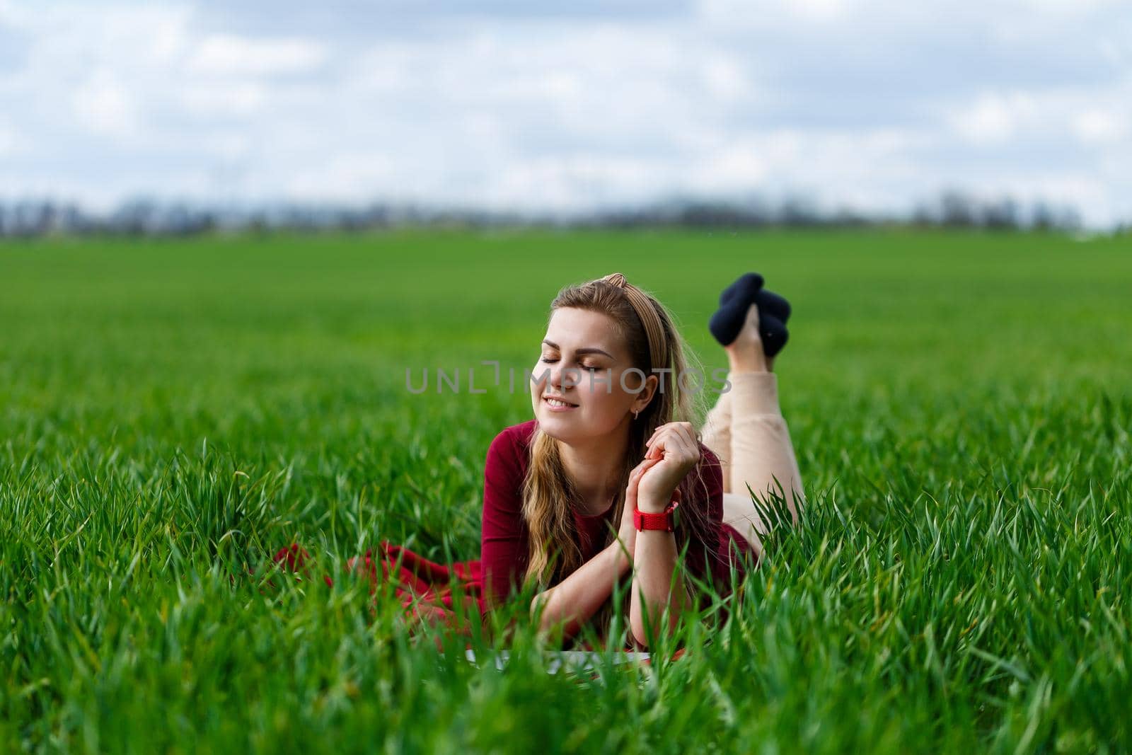 Young beautiful woman student with a laptop lies on the grass. Work outdoors.