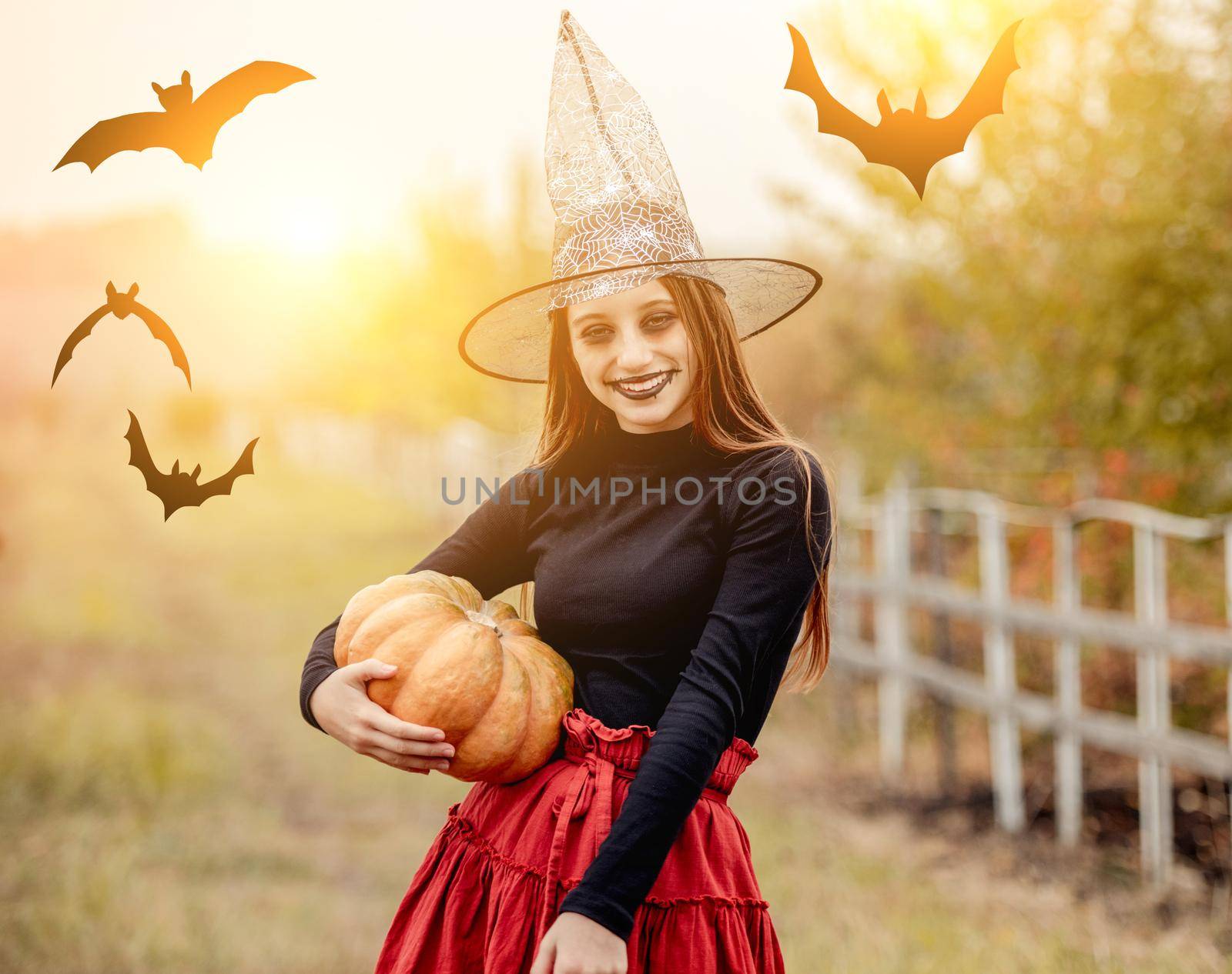 halloween portrait of teenage girl in witch hat with pumpkin