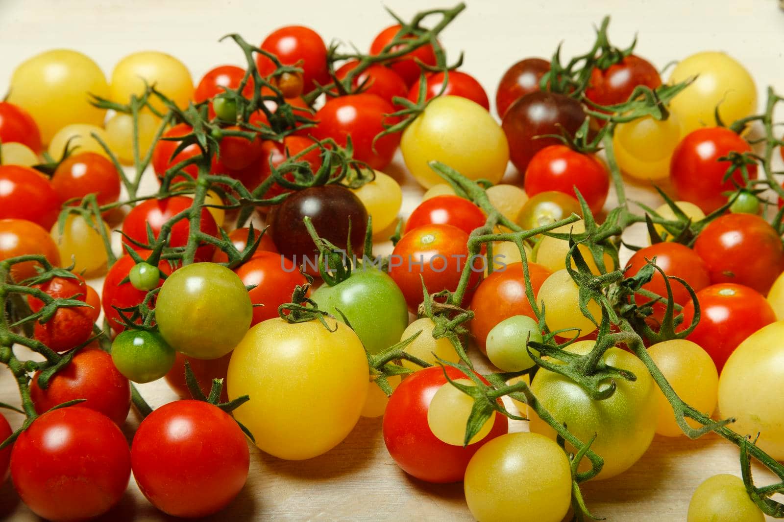 Little red, yellow, green and black cherry tomatoes on white table, nature background, pattern, selective focus.
