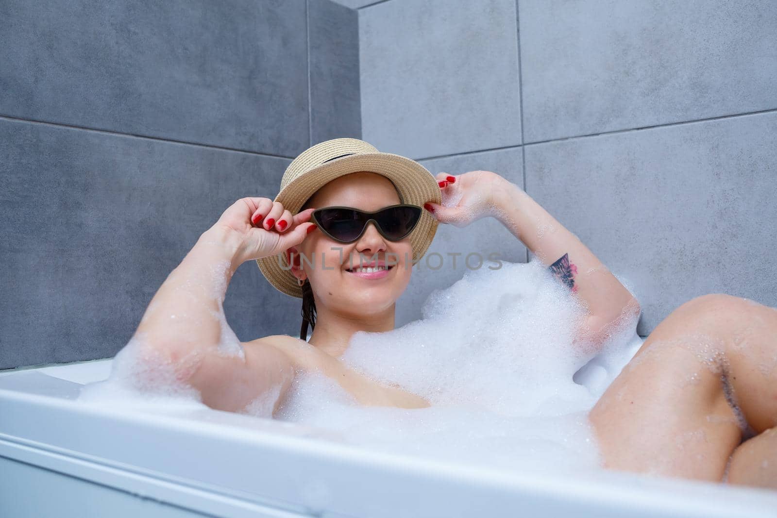 Young woman in sunglasses takes a bath at home. Relax after a hard day.