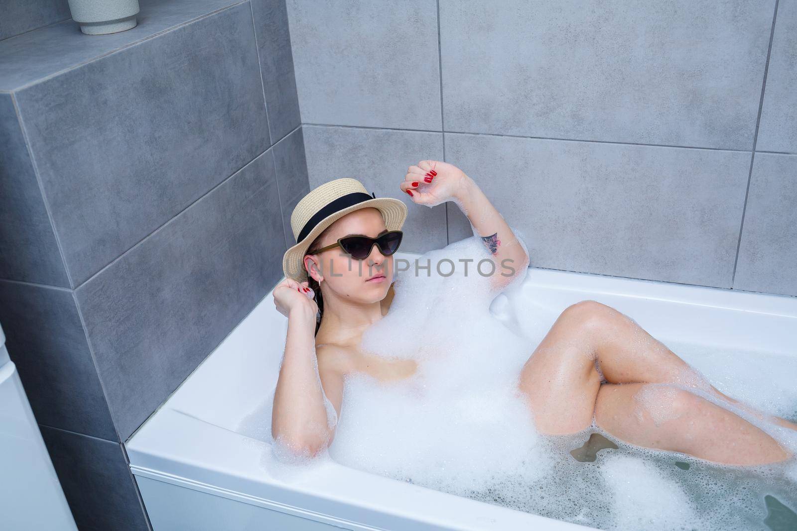 Young woman in sunglasses takes a bath at home. Relax after a hard day.