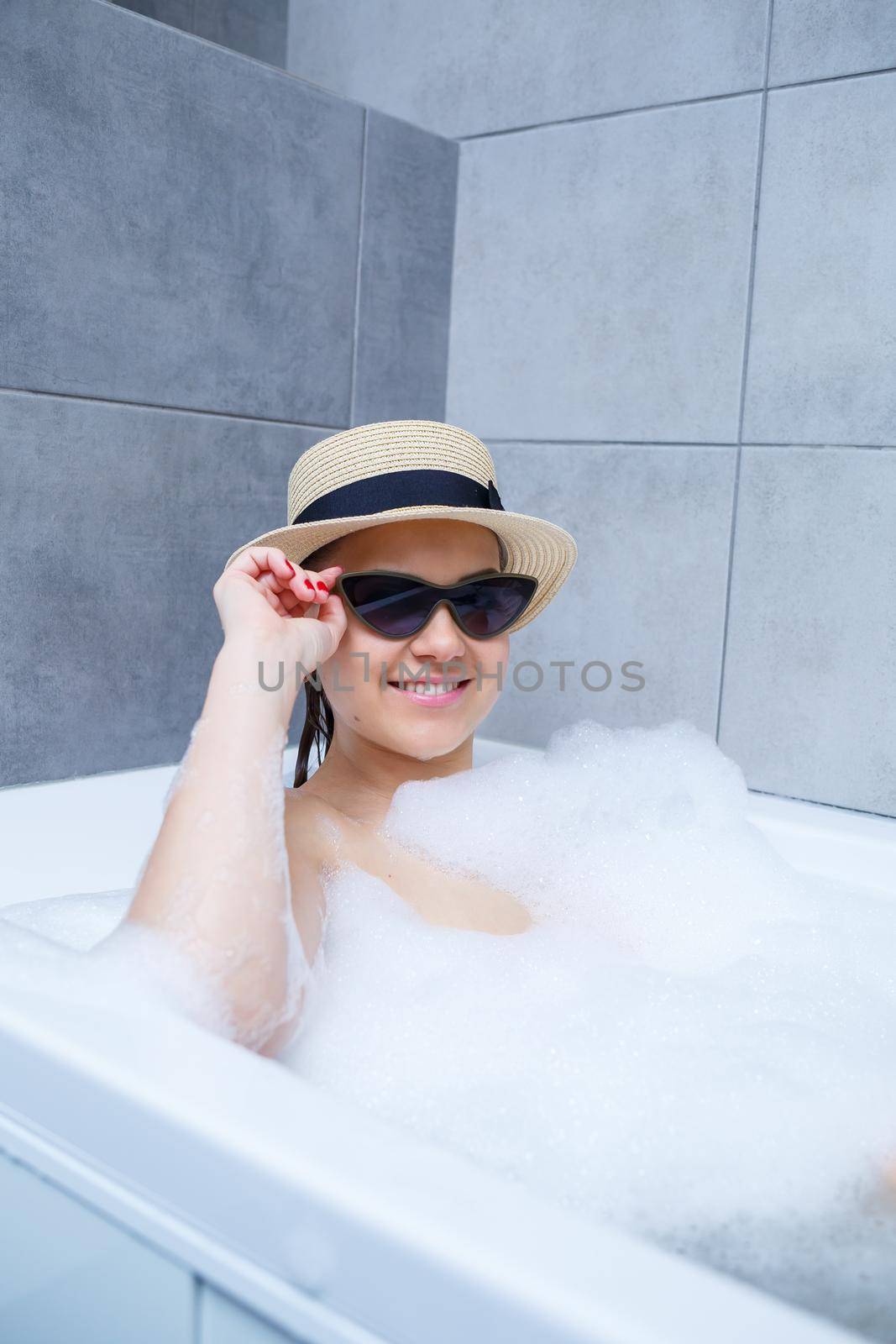 Young woman in a hat and sunglasses takes a bath at home. Relax after a hard day. The spa is a relaxing procedure.