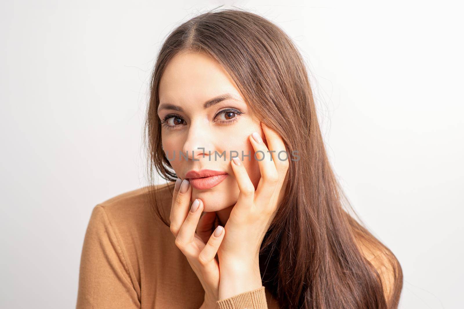 Portrait of the caucasian female model touching face with manicured fingers isolated on white background