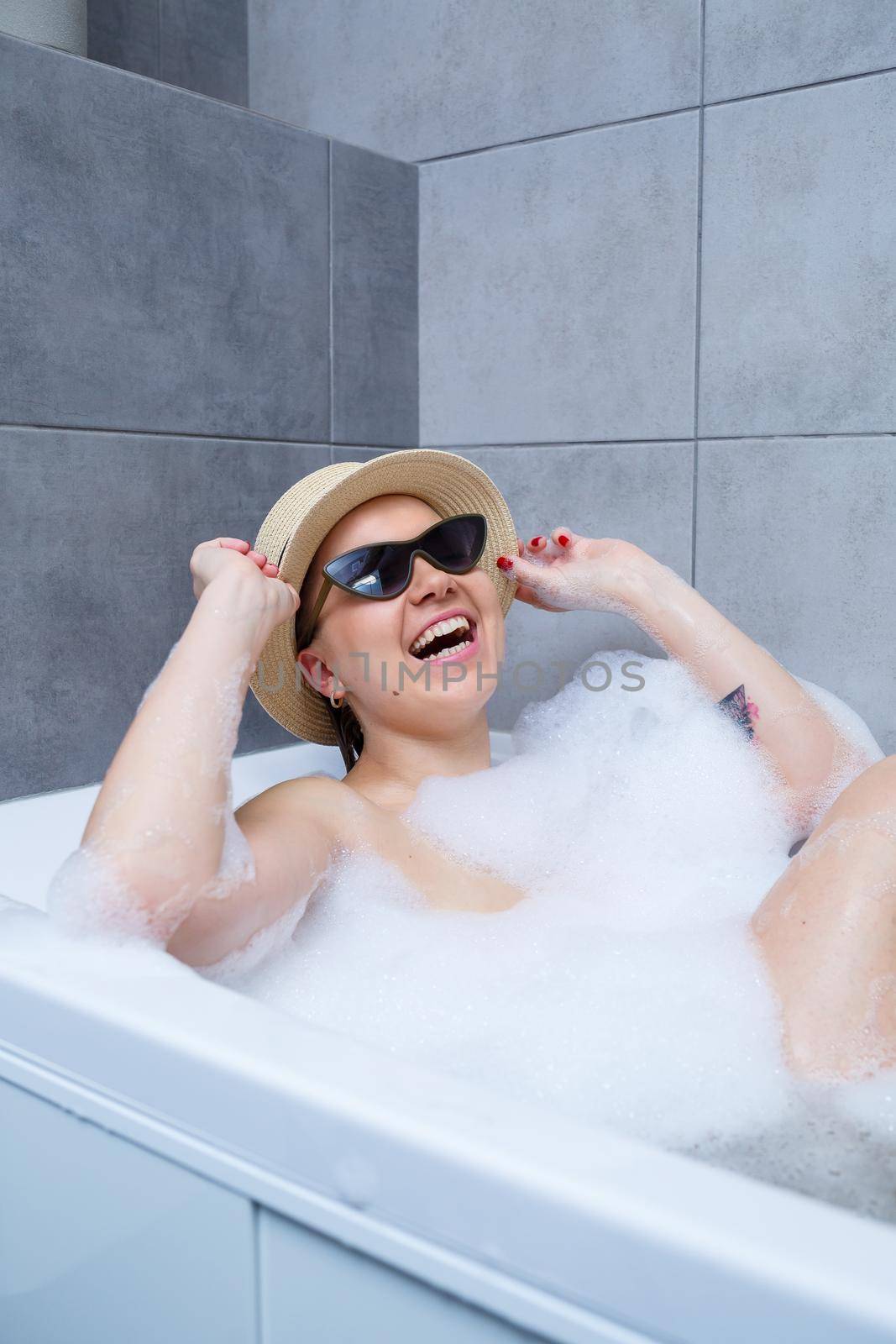 Young woman in a hat and sunglasses takes a bath at home. Relax after a hard day. The spa is a relaxing procedure.
