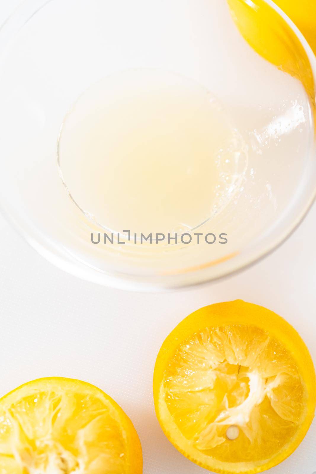 Zesting and juicing fresh lemon on a white cutting board.