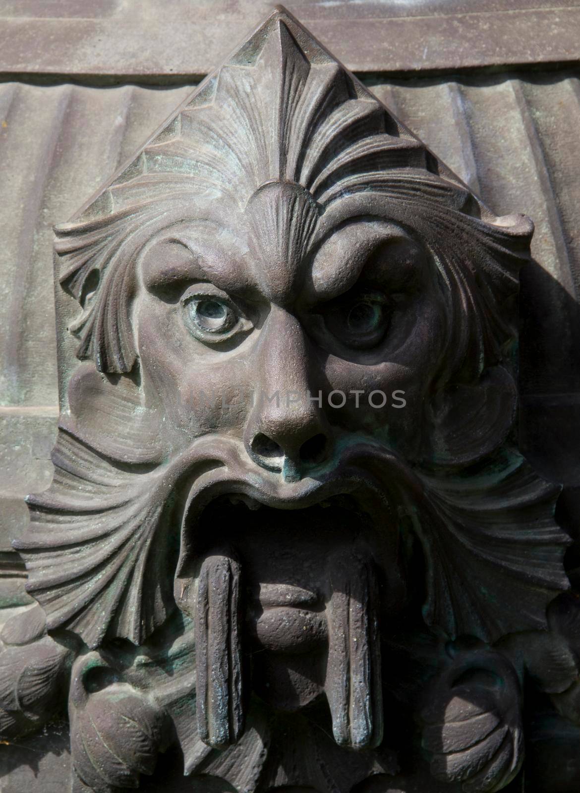 Demonic statue face made of metal on a street lamp by gallofoto