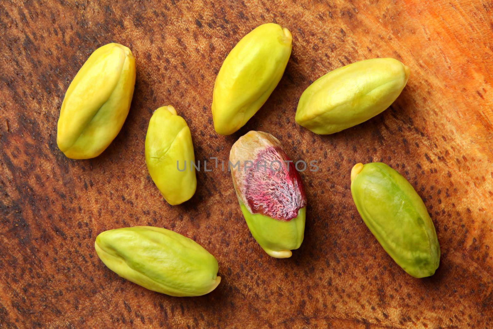 Close up photo - peeled green pistachios on wooden board. View from above