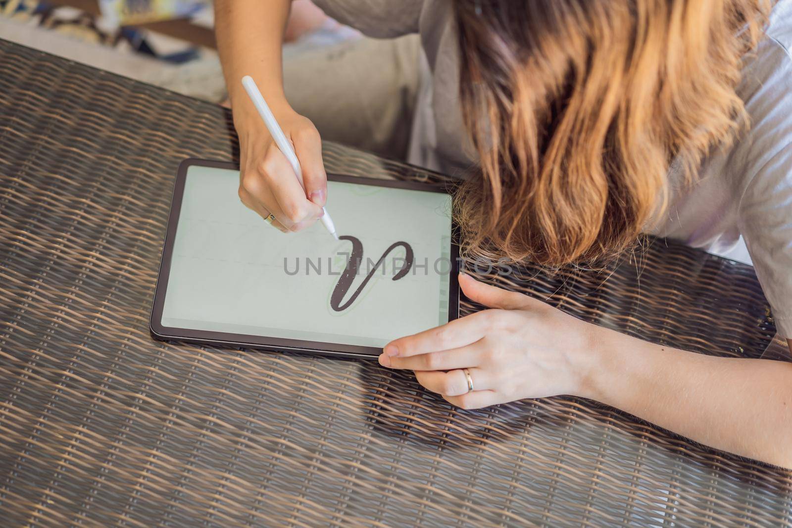 Calligrapher Young Woman writes phrase on digital tablet. Inscribing ornamental decorated letters. Calligraphy, graphic design, lettering, handwriting, creation by galitskaya