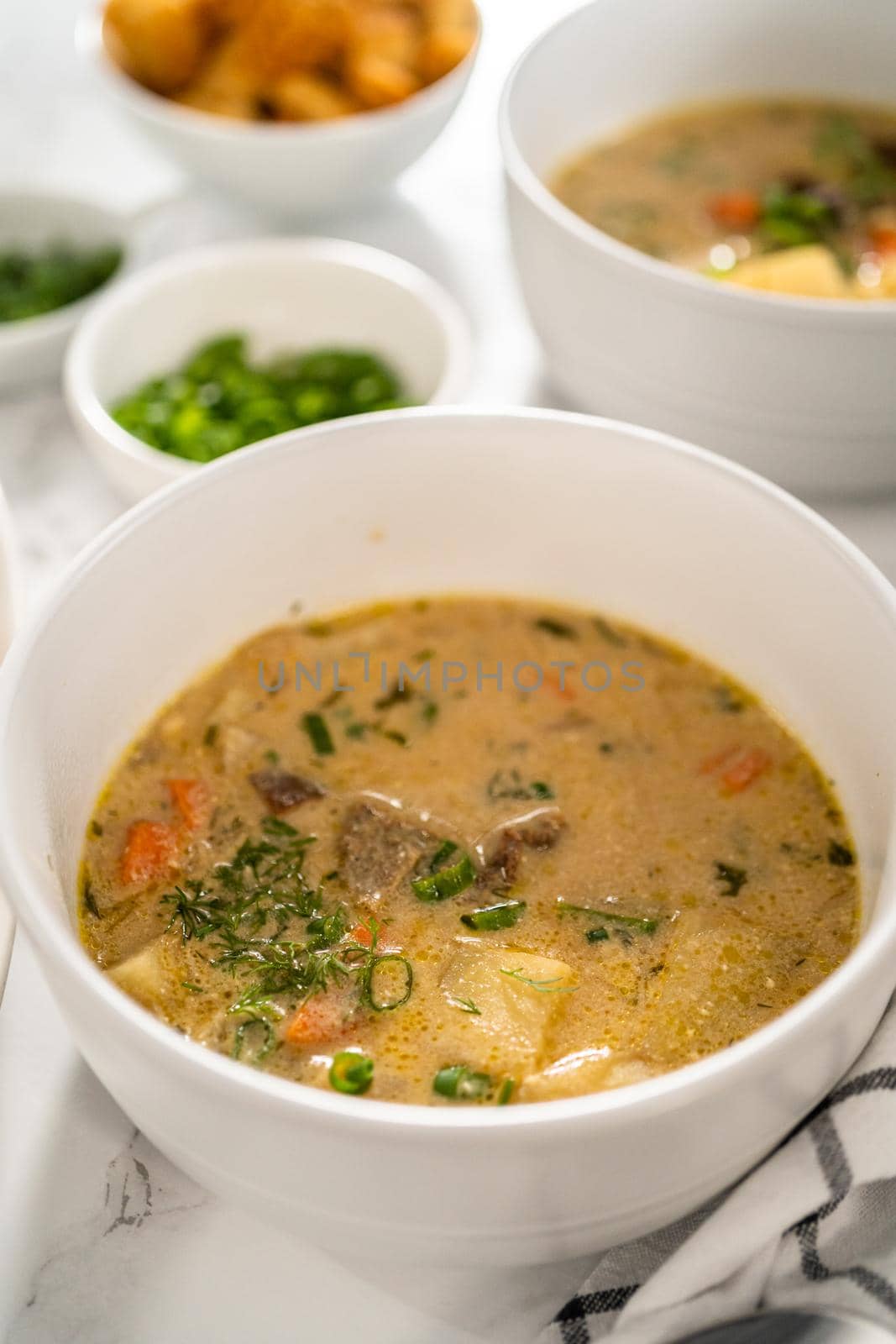 Serving creamy wild mushroom soup made out of dehydrated wild mushrooms in white bowls with sourdough bread.