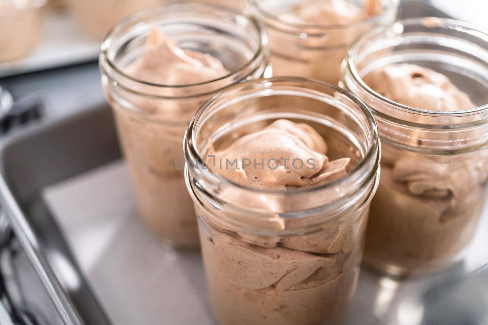 Scooping mixture into the small glass jars to make homemade chocolate ice cream.