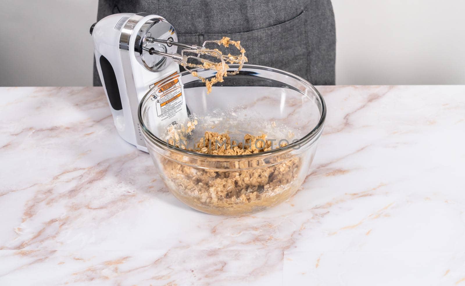 Mixing ingredients in a large glass mixing bowl to bake apple oatmeal cookies.