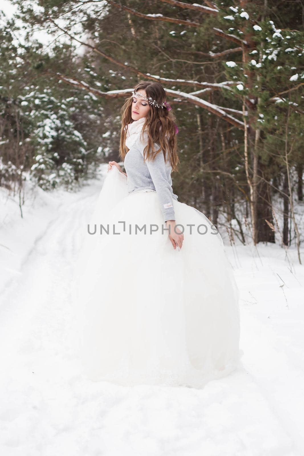 Beautiful bride in a white dress with a bouquet in a snow-covered winter forest. Portrait of the bride in nature by Annu1tochka