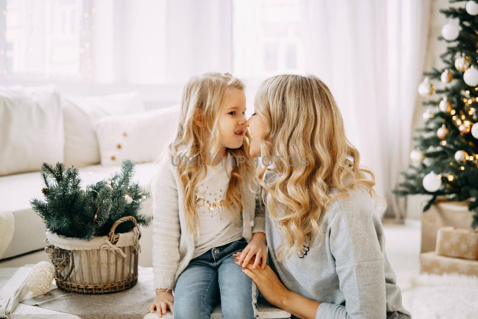 Happy family: mother and daughter. Family in a bright New Year's interior with a Christmas tree.