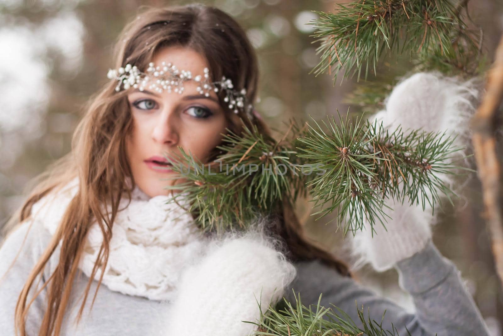 Beautiful bride in a white dress with a bouquet in a snow-covered winter forest. Portrait of the bride in nature.