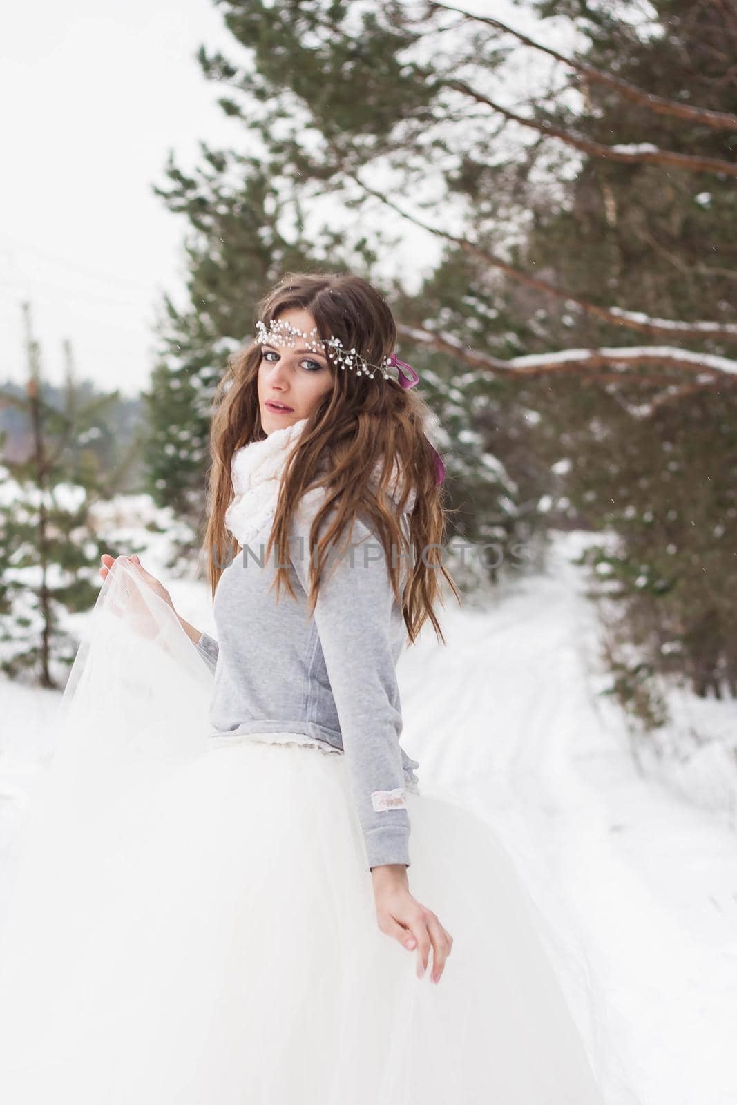 Beautiful bride in a white dress with a bouquet in a snow-covered winter forest. Portrait of the bride in nature.