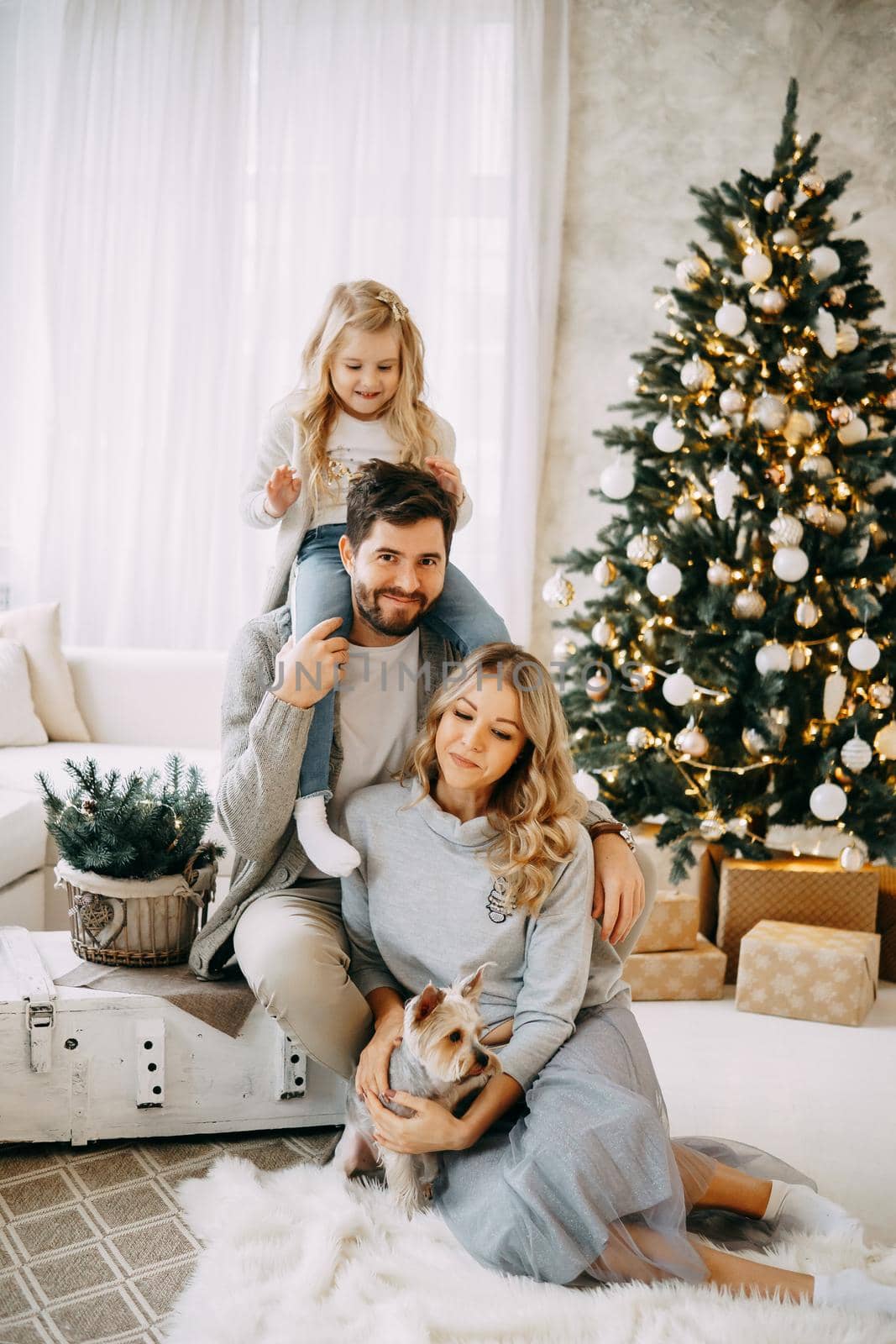 Happy family: mom, dad and pet. Family in a bright New Year's interior with a Christmas tree.