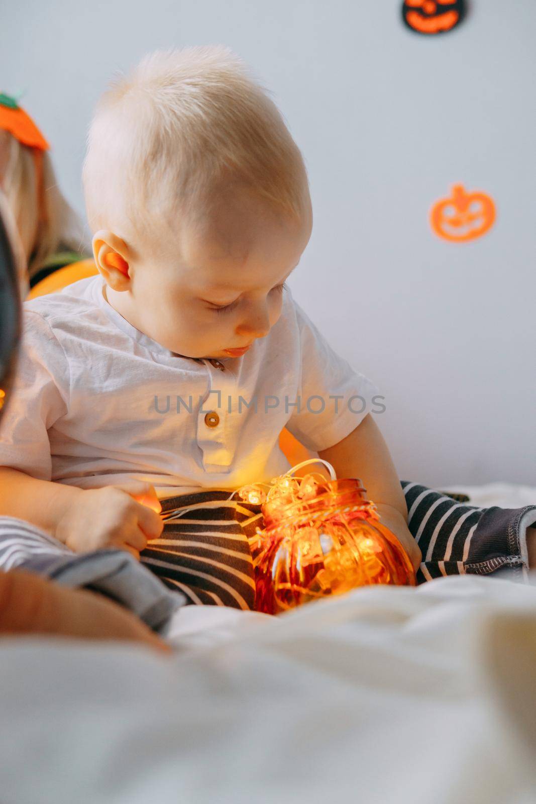 Children's Halloween - a boy in a carnival costume with orange and black balloons at home. Ready to celebrate Halloween.