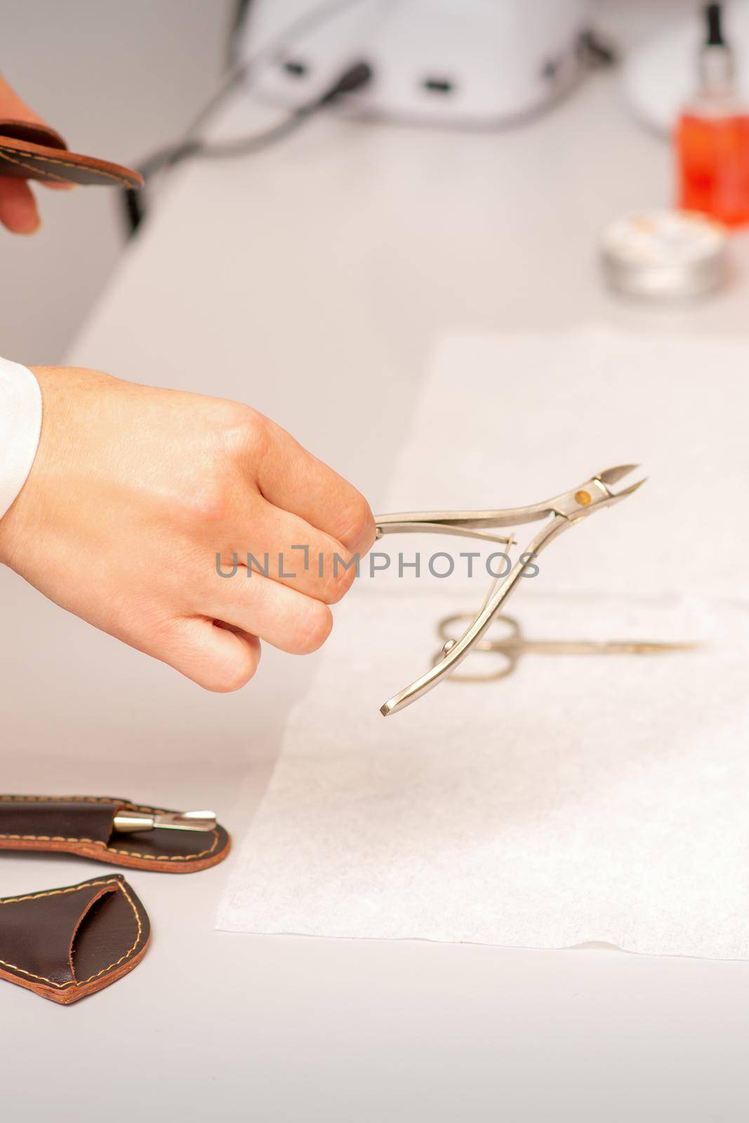Nail nippers in the hand of female manicure master putting to the towel before nail care in manicure salon