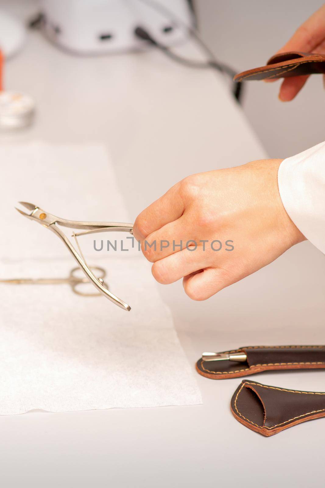 Nail nippers in the hand of female manicure master putting to the towel before nail care in manicure salon