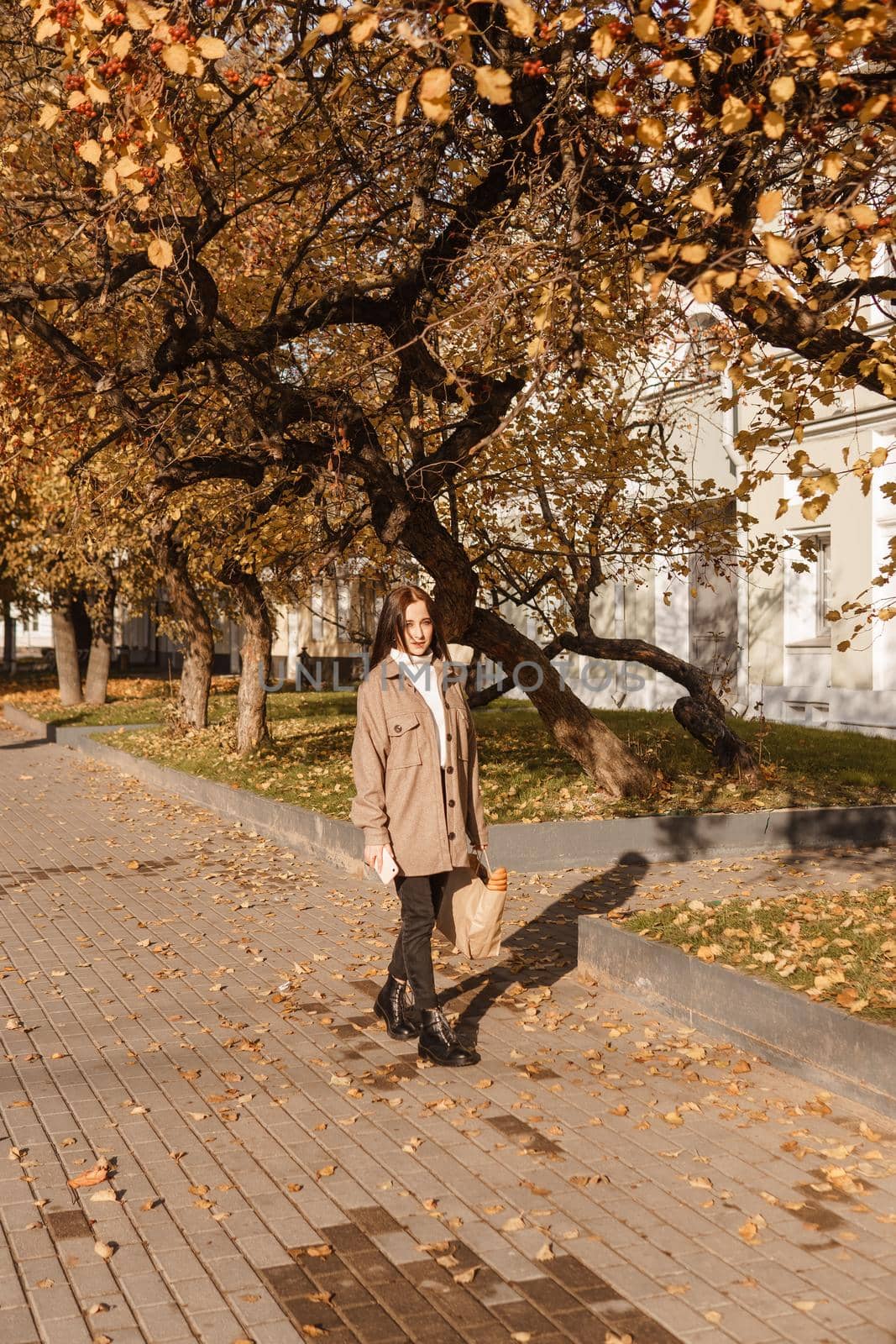 A stylish brunette woman walks around the autumn city. The season is autumn.
