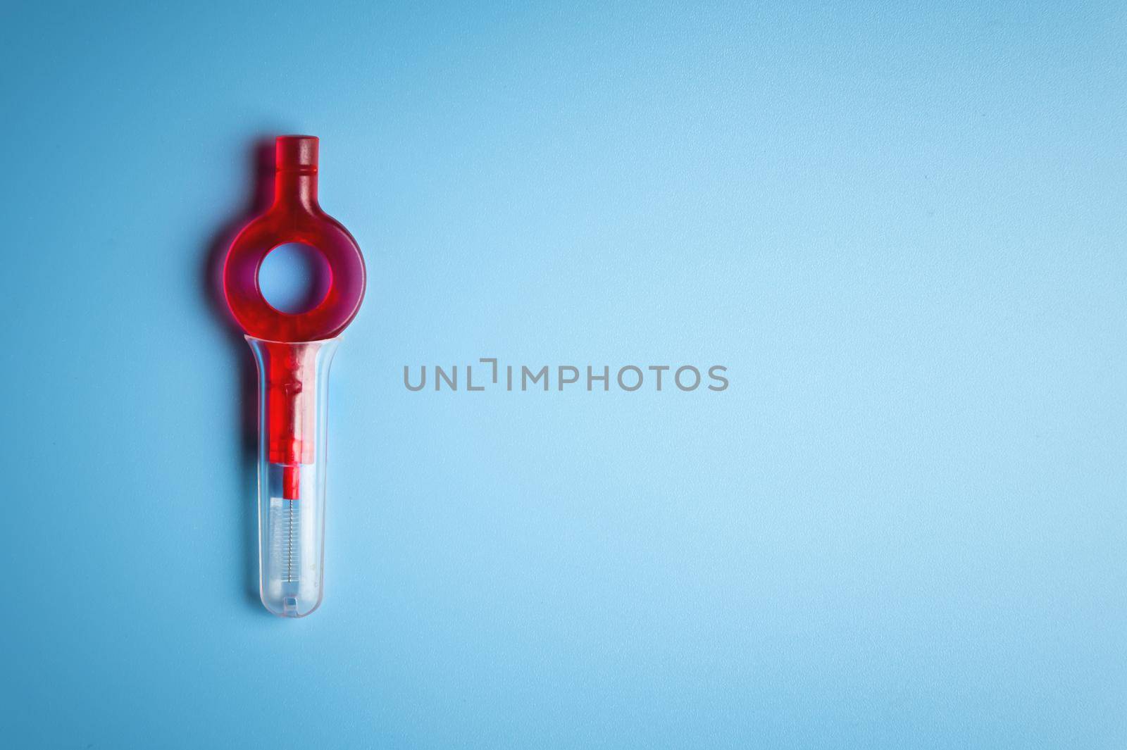 Red orthodontic tool toothbrush, lies on a blue background, studio shot, no one.