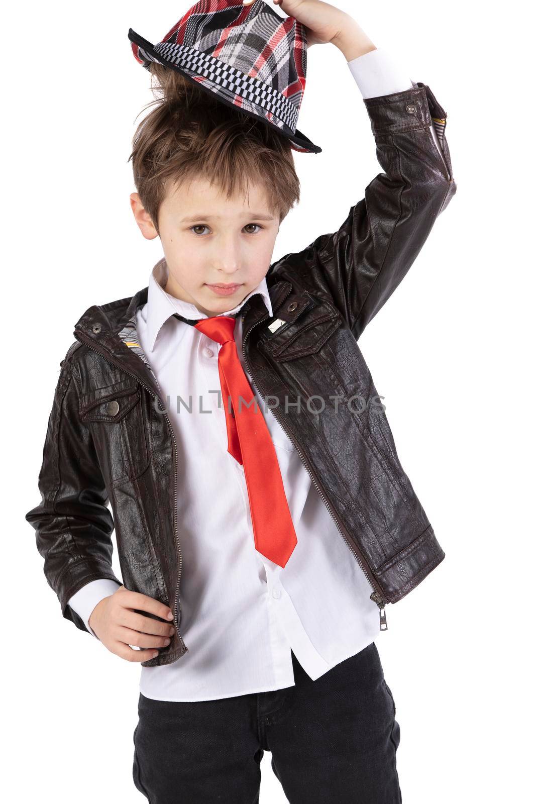 Funny little boy in a leather jacket, elegant hat and red tie. Red child on a white background. Seven year old boy. Take off your hat.