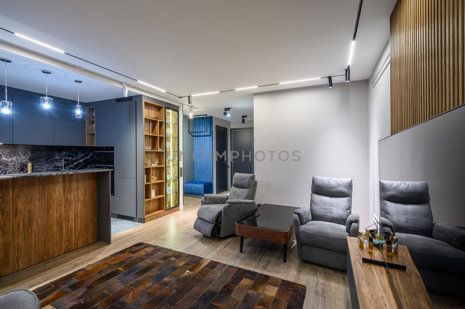 Luxury living room with massage chairs and grey kitchen in studio apartment interior