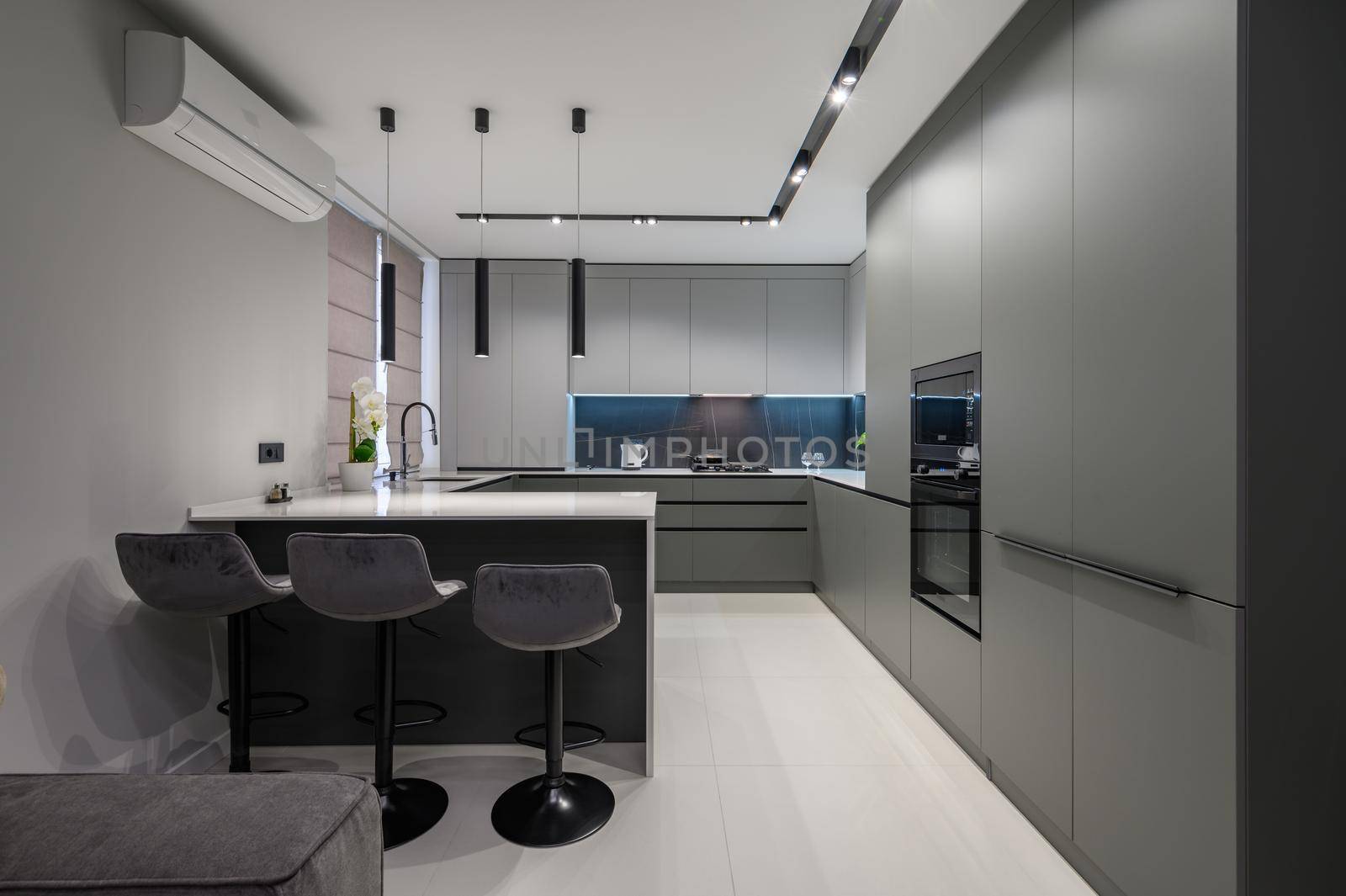 Elegant white and grey luxury kitchen, dining room with kitchen bar and stools in studio apartment interior