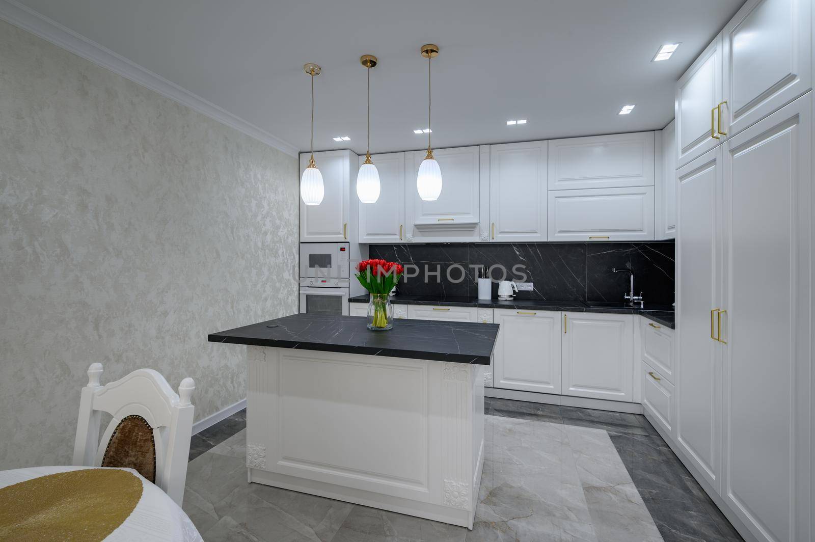 White large modern domestic kitchen with island and black marble worktop