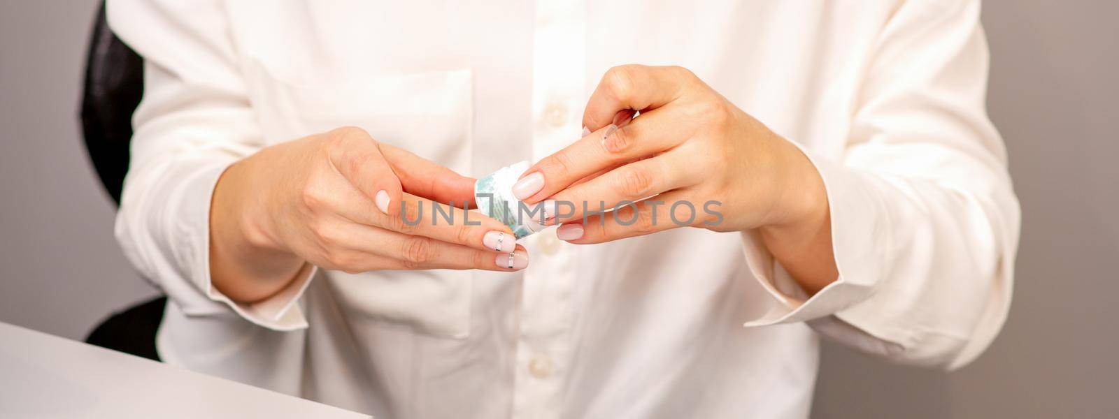 Manicure master's hands with beautiful manicure holding case box with nail sequins in nail salon. by okskukuruza