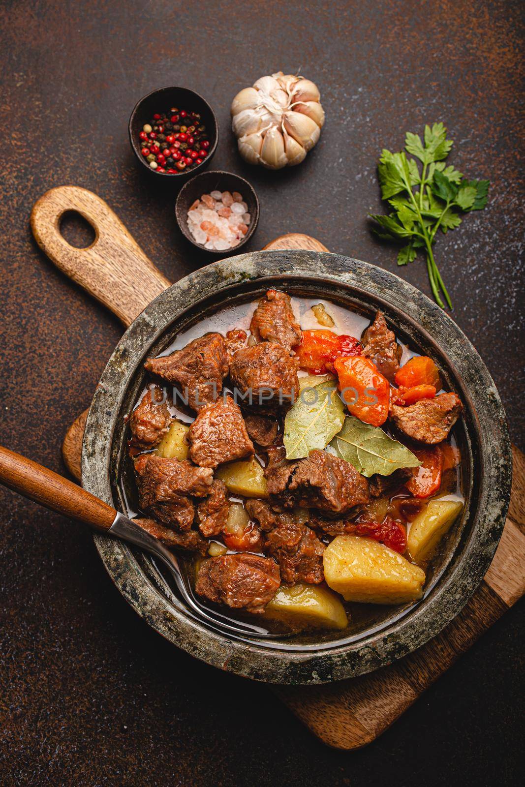 Meat beef stew with vegetables and gravy in rustic metal pot top view by its_al_dente