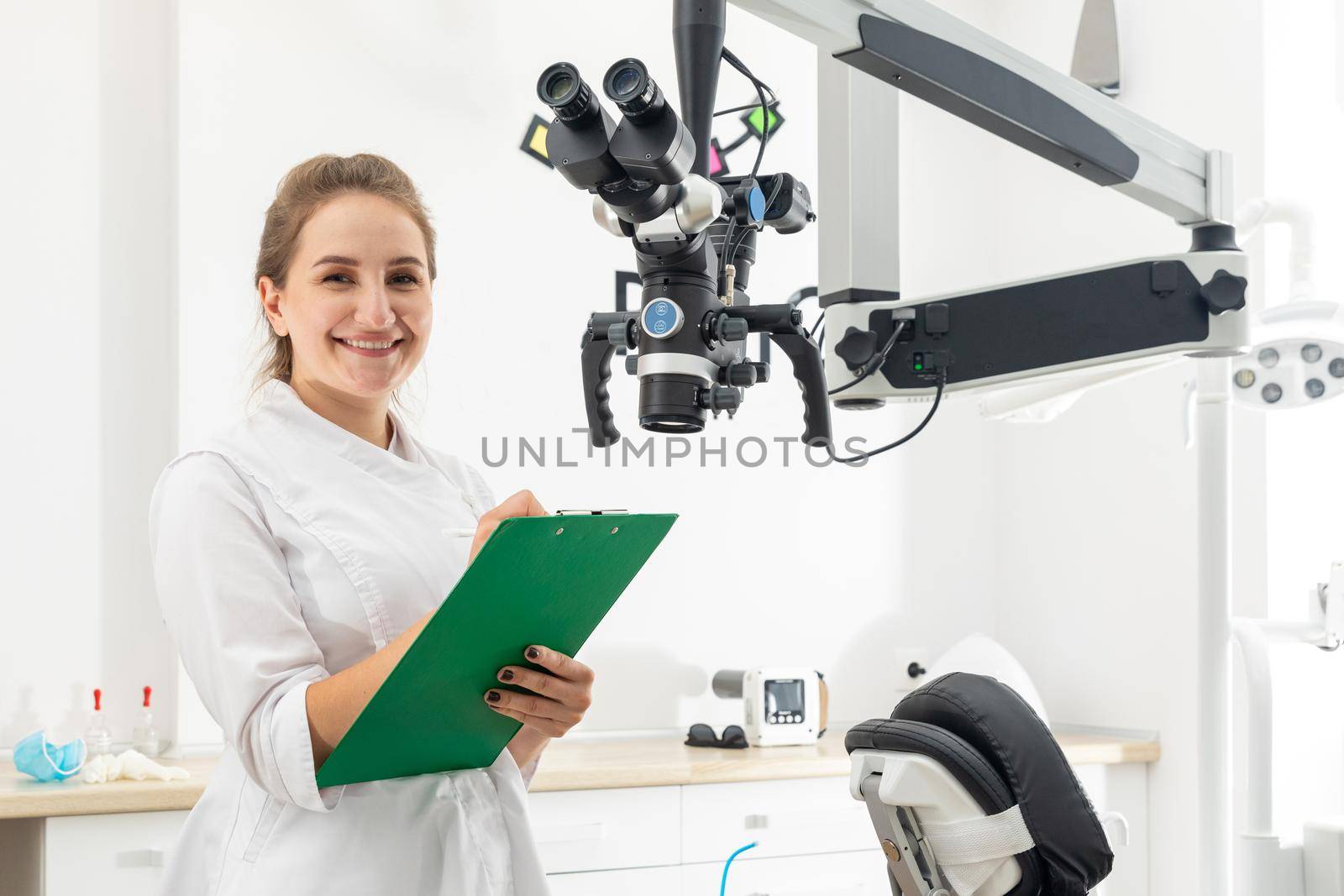 Smiling female dentist holding a clipboard with patient records in hands at dental clinic