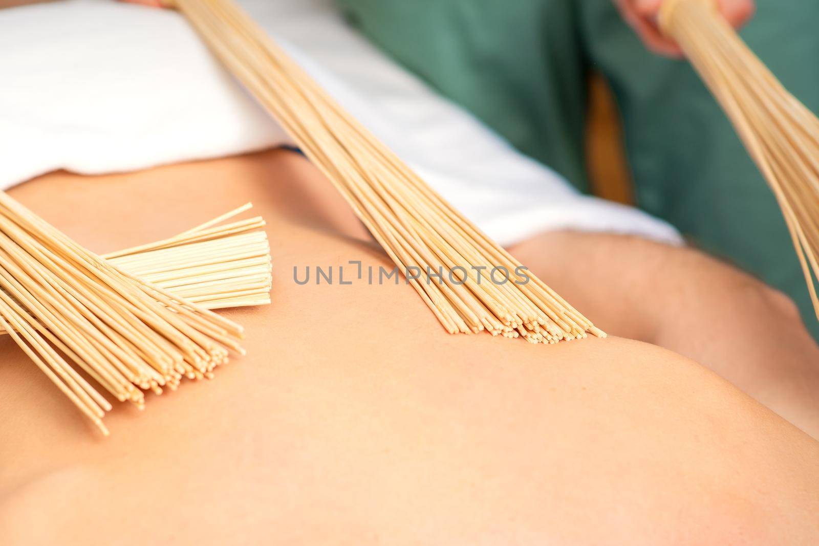 Young man have double samurai massage with bamboo brooms in spa. Relaxation massage concept